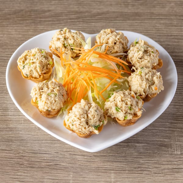 Heart-shaped plate with eight crab salad tartlets, garnished with shredded lettuce and carrots.