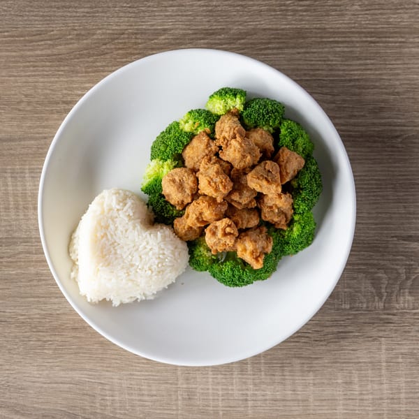 Fried chicken pieces surrounded by broccoli florets, with a heart-shaped mound of white rice.